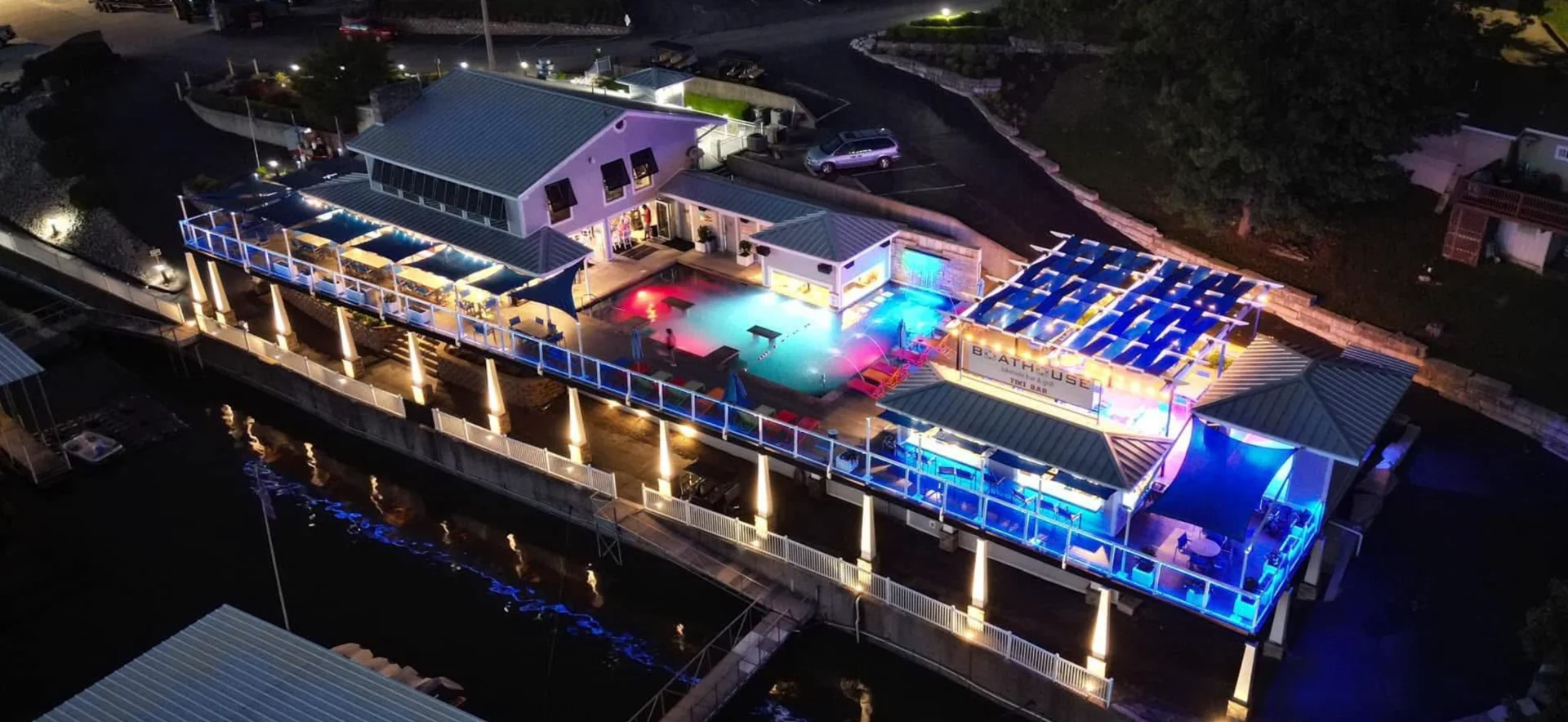 Aerial nighttime view of the Boathouse waterfront restaurant, pool and illuminated dining decks at Village Marina